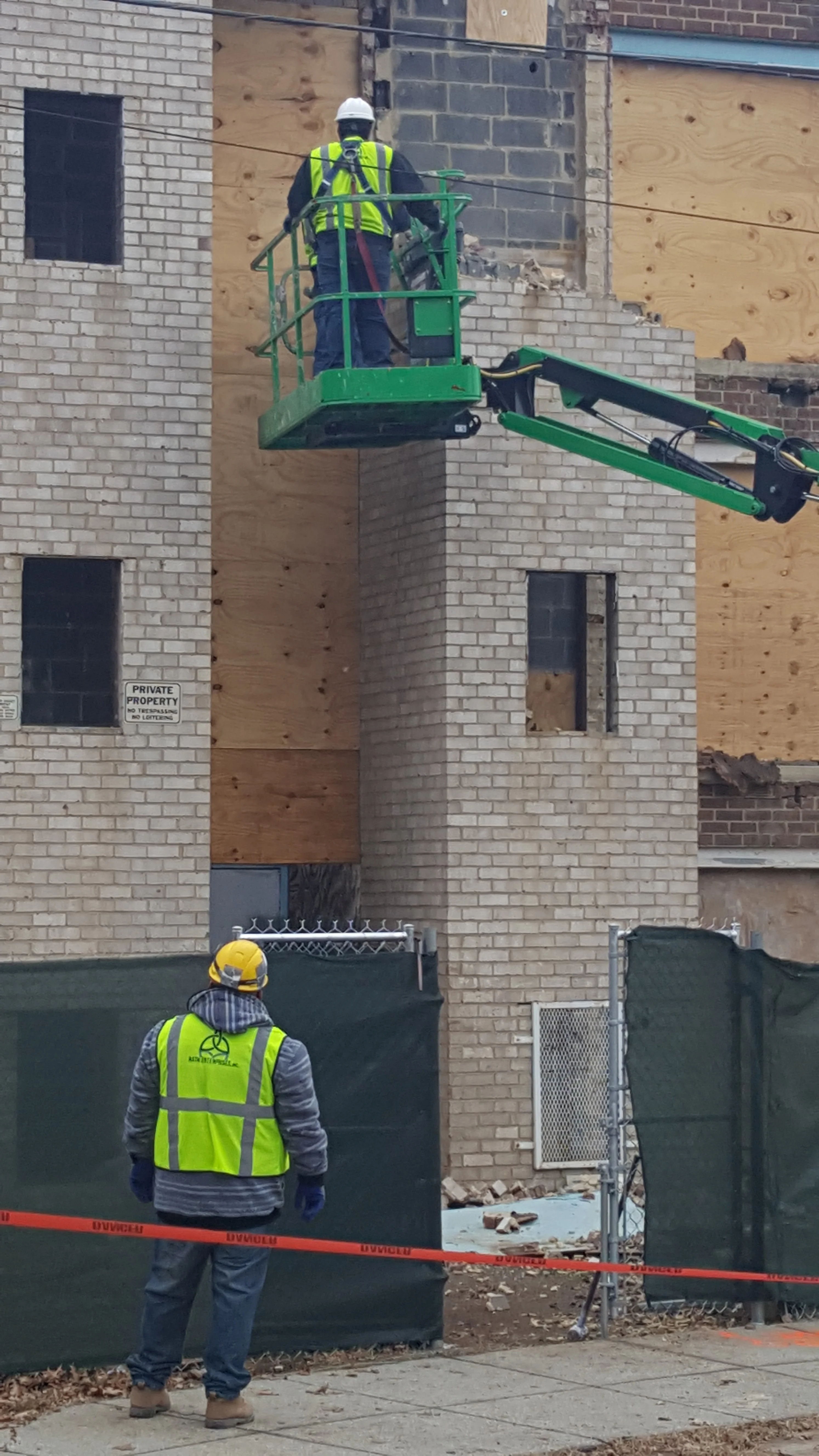 Worker on elevated platform removing asbestos from brick building facade in Washington, DC