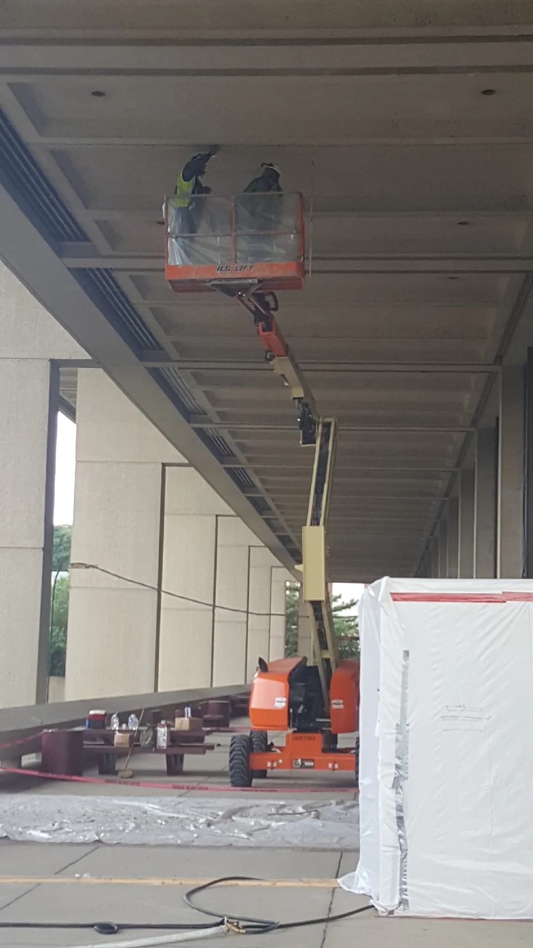 Workers on aerial lift removing asbestos from commercial concrete ceiling